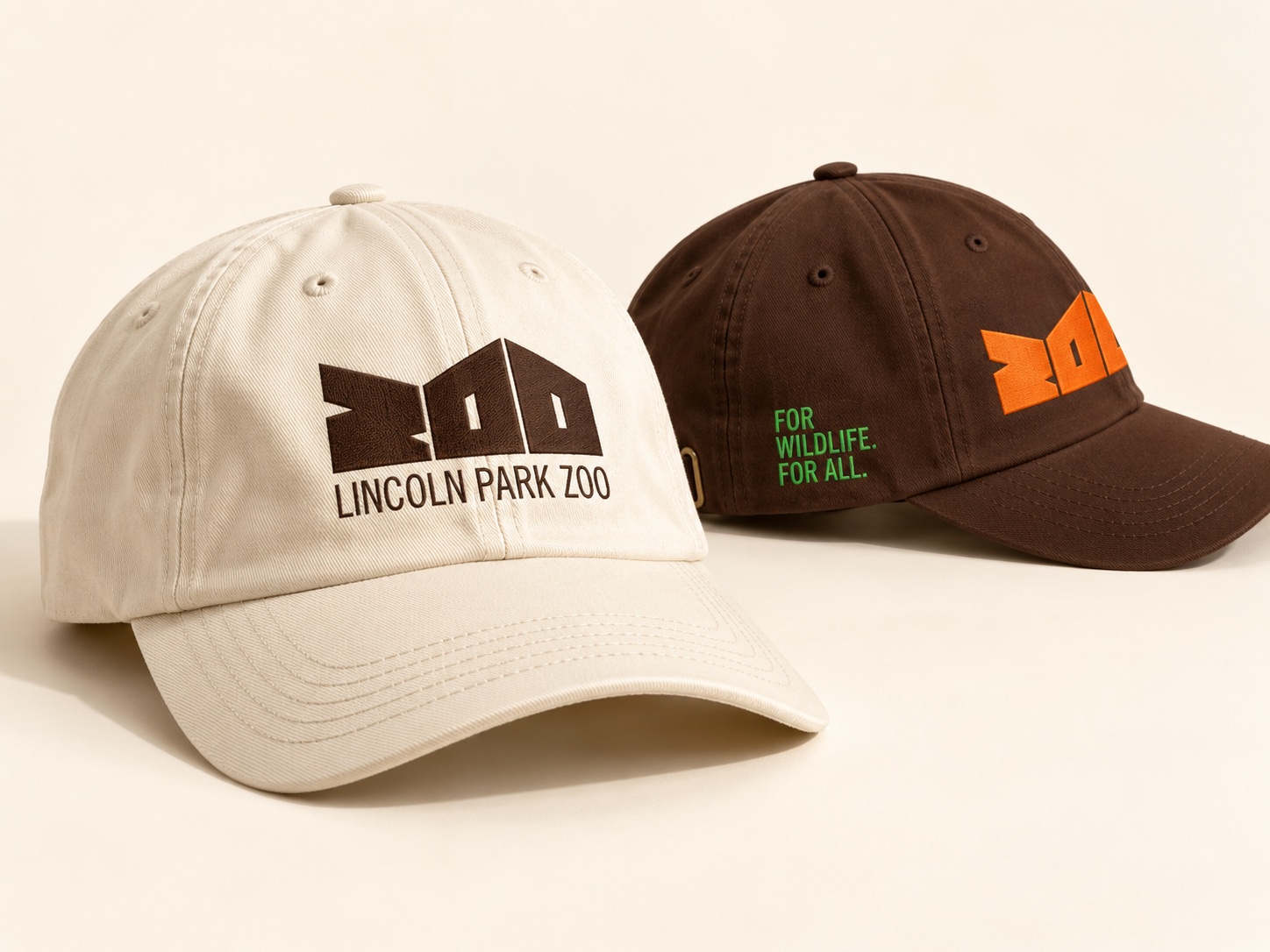 Cream and brown Lincoln Park Zoo caps, one embroidered For Wildlife. For All.