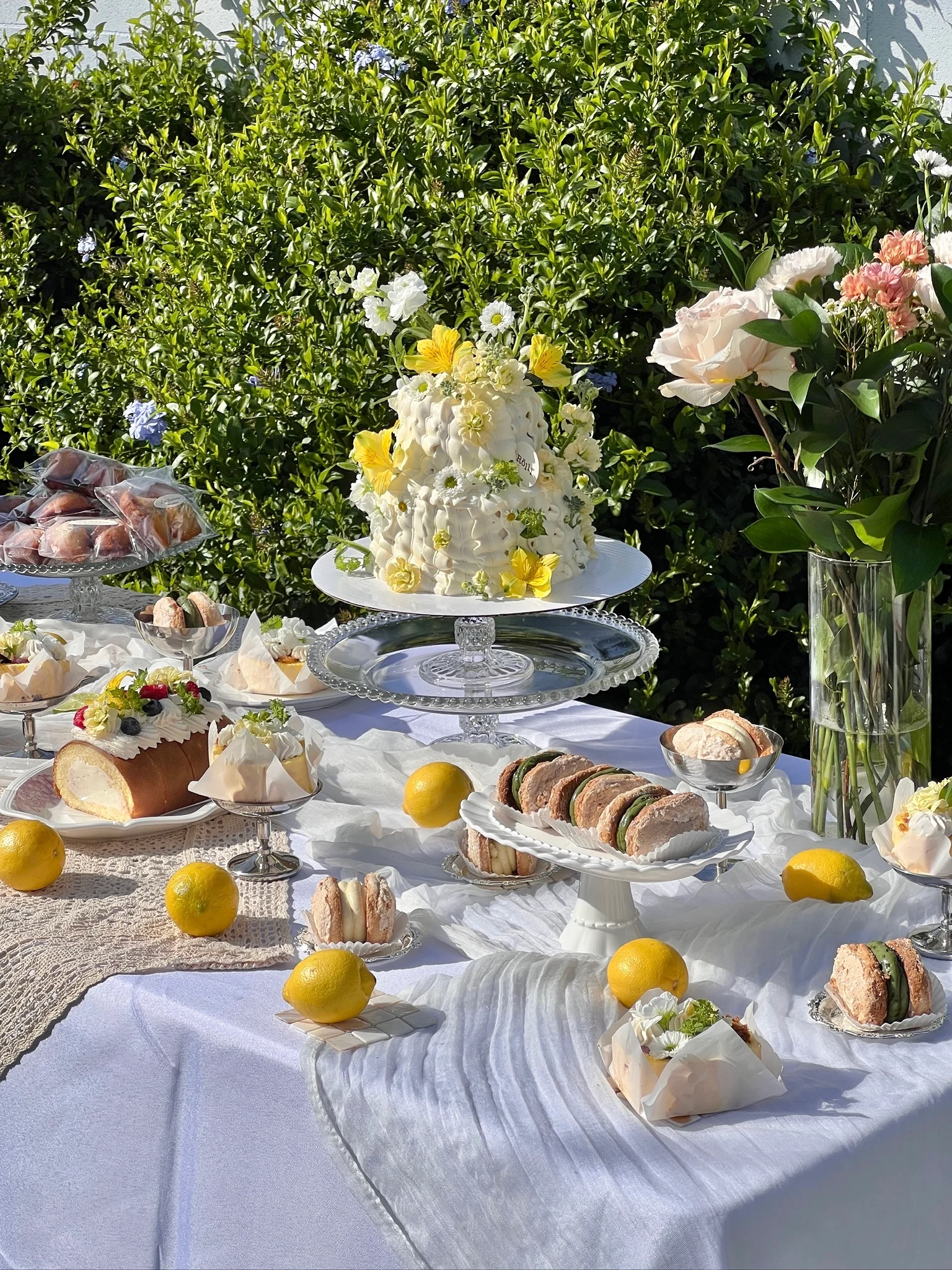 Outdoor dessert table with a flower-topped cake and pastries