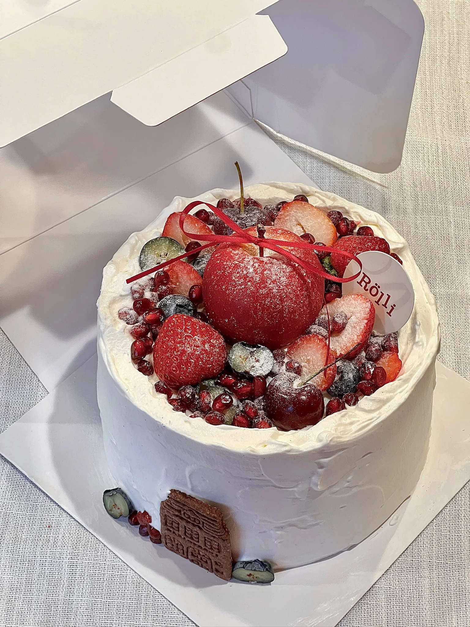 White cake topped with strawberries and pomegranate