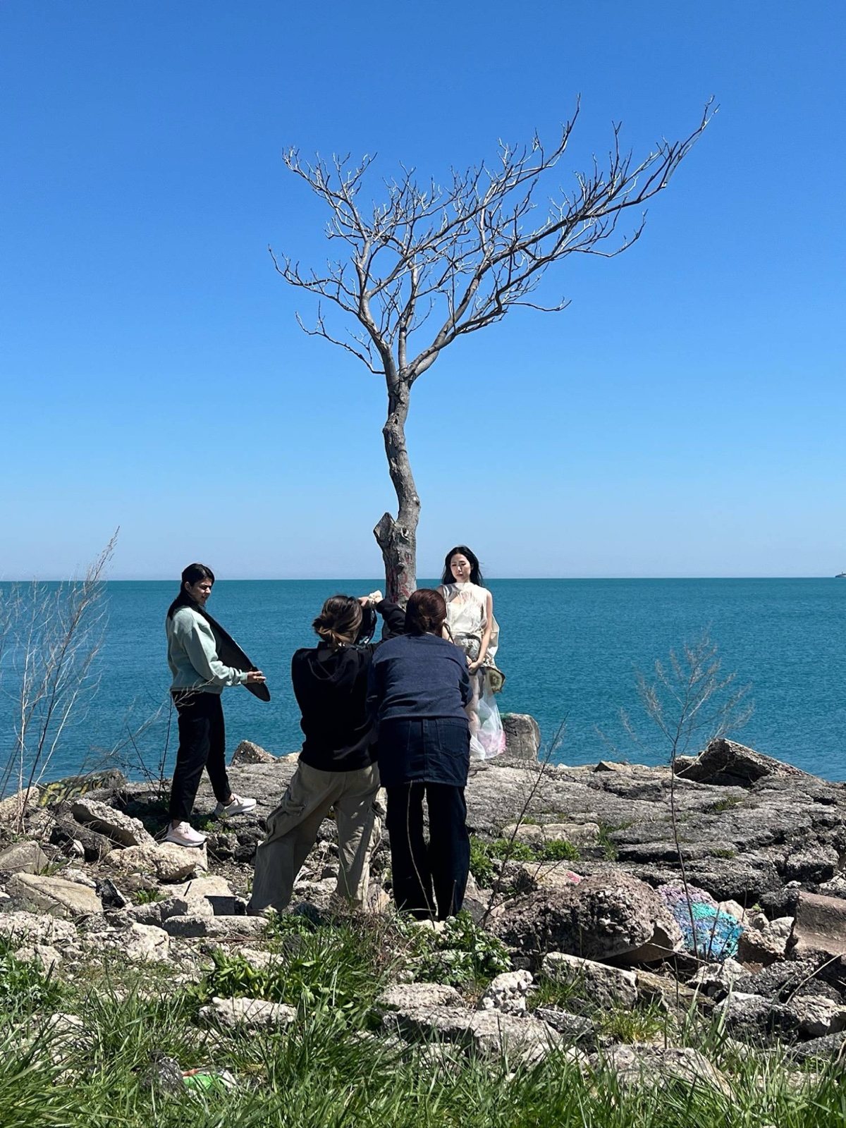 The crew shooting by a bare tree on the shore